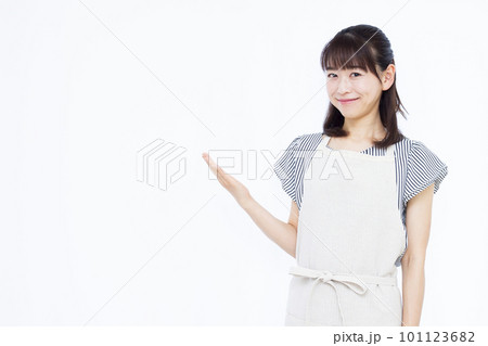 白い背景の前で案内をしているエプロン姿の30代主婦 101123682
