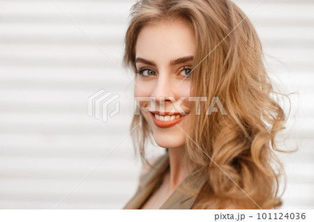 Portrait of a cute charming girl with a wonderful smile with natural make-up with curly hair with blue eyes on a white background. Happy positive young woman. Close-up. 101124036