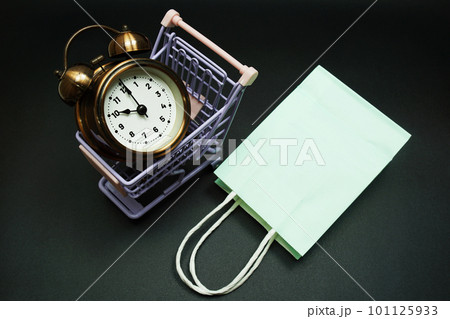 Trolley cart and shopping bag with alram clock with space copy on black background Trolley cart and shopping bag with alram clock with space copy on black background 101125933