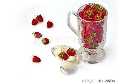 Red raspberries in a glass gravy boat with cream and in a glass goblet 101126839
