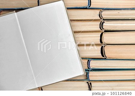 Open vintage book or notebook with blank pages lies on the background of a row of shabby books Open vintage book or notebook with blank pages lies on the background of a row of shabby books 101126840