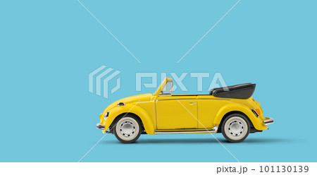 Miniature yellow toy convertible car on blue background with copyspace 101130139