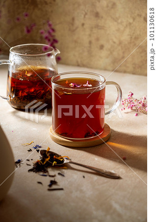 Glass cup of loose black leaf tea with dried flowers. Drinking tea concept. Soft focus 101130618
