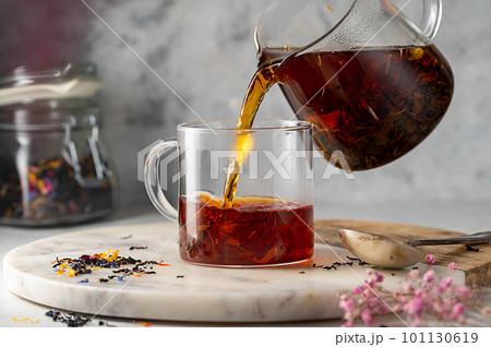 Pouring freshly brewed black loose leaf tea in glass cup. Lifestyle drinking tea. 101130619