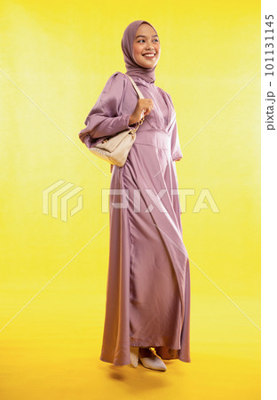 portrait of Muslim woman standing wearing dress on yellow portrait of Muslim woman standing wearing dress on yellow 101131145
