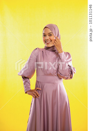 attractive Asian muslimah woman wearing pink dress on yellow background attractive Asian muslimah woman wearing pink dress on yellow background 101131146