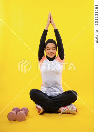 Asian Muslim woman in sportswear practicing yoga with hands together 101131261