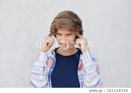 Portrait of handsome male with trendy hairstyle holding fingers on temples trying to concentrate and to get idea having serious and thoughtful look. Teenager remembering something important in life 101138339