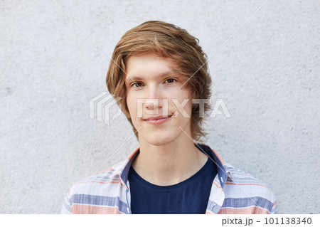 Close up of handsome male with dark eyes, pure healthy skin and thin lips looking directly into camera with serious expression. Hipster boy with appealing appearance posing against white wall Close up of handsome male with dark eyes, pure healthy skin and thin lips looking directly into camera with serious expression. Hipster boy with appealing appearance posing against white wall 101138340