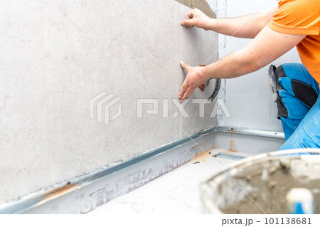 installation of large format tiles on the wall by a craftsman 101138681