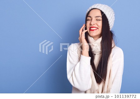 Cheerful pretty brunette girl talking on phone and laughing carefree, holding smartphone near ear, standing isolated over blue background, copy space for advertisement for promo. Cheerful pretty brunette girl talking on phone and laughing carefree, holding smartphone near ear, standing isolated over blue background, copy space for advertisement for promo. 101139772