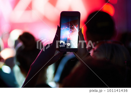 Hand with a phone records live music festival. People taking photographs with smart phone during concert. 101141436