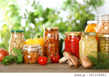 Glass jars of different pickled vegetables on wooden table Glass jars of different pickled vegetables on wooden table 101142061