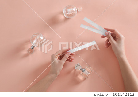 Woman with perfume testing stripes on peach background, top view Woman with perfume testing stripes on peach background, top view 101142112