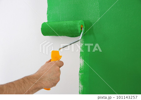 Man painting white wall with green dye, closeup. Interior renovation 101143257