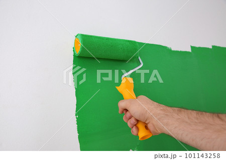 Man painting white wall with green dye, closeup. Interior renovation 101143258