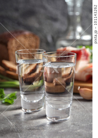 Cold Russian vodka with snacks on grey table, closeup Cold Russian vodka with snacks on grey table, closeup 101143262