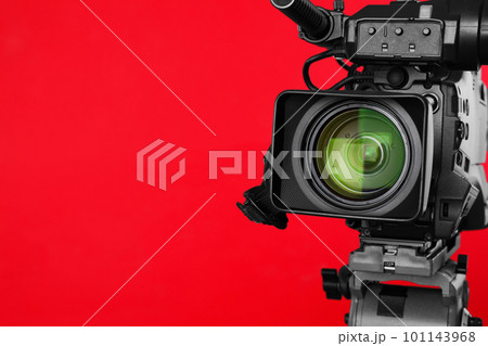 Modern professional video camera on red background, closeup. Space for text 101143968