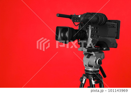 Modern professional video camera on red background Modern professional video camera on red background 101143969