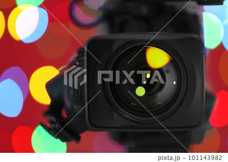 Modern video camera against blurred colorful lights, closeup Modern video camera against blurred colorful lights, closeup 101143982