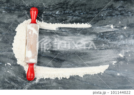 Flour and rolling pin on grey marble table, top view. Space for text Flour and rolling pin on grey marble table, top view. Space for text 101144022