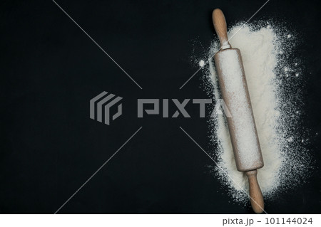 Flour and rolling pin on black table, top view. Space for text Flour and rolling pin on black table, top view. Space for text 101144024