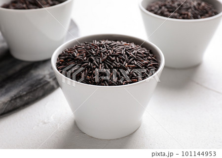 Uncooked brown rice in bowl on white table, closeup 101144953