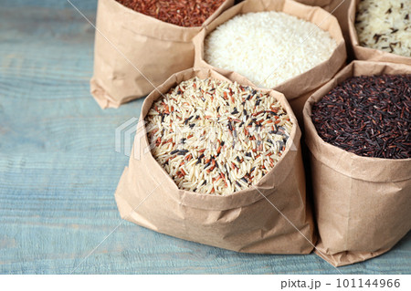 Brown and polished rice in paper bags on blue wooden table Brown and polished rice in paper bags on blue wooden table 101144966