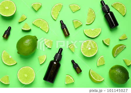 Flat lay composition with lime essential oil on green background 101145027