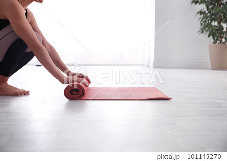 Woman rolling her mat on floor in yoga studio, closeup Woman rolling her mat on floor in yoga studio, closeup 101145270