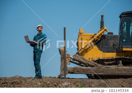 Caucasian male builder in hardhat holding laptop at construction site. Caucasian male builder in hardhat holding laptop at construction site. 101145334