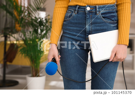 Professional journalist with modern microphone and notebook in room, closeup 101145370