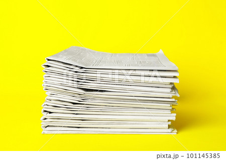 Stack of newspapers on yellow background. Journalist's work 101145385