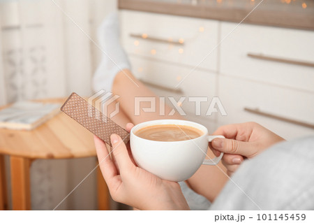 Woman having delicious wafer and coffee for breakfast indoors, closeup Woman having delicious wafer and coffee for breakfast indoors, closeup 101145459