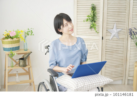 リビングでノートパソコンを使いながら想像する車椅子に乗った女性 101146181