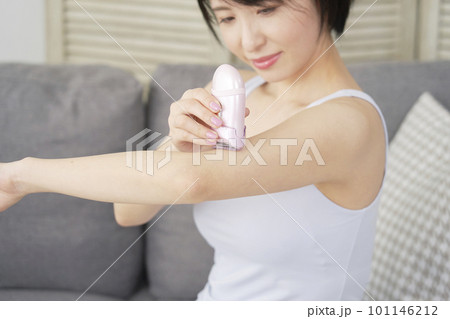 リビングで家庭用脱毛器で腕のセルフ脱毛をする女性 101146212