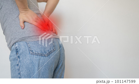 Caucasian woman feels pain in her back. Faceless girl keeps her hands on her lower back.  101147599