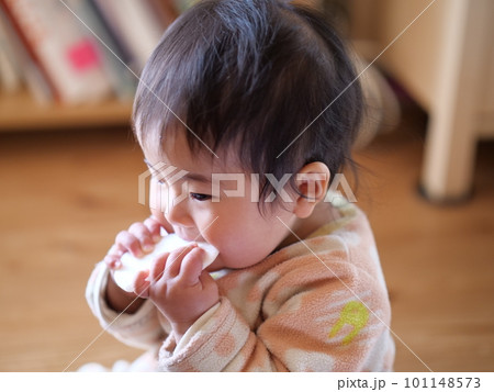 美味しそうにおせんべいを食べる0歳の女の子の写真 101148573