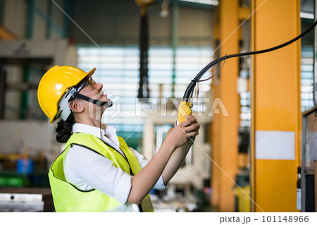 Factory female worker use remote control to lift crane 101148966