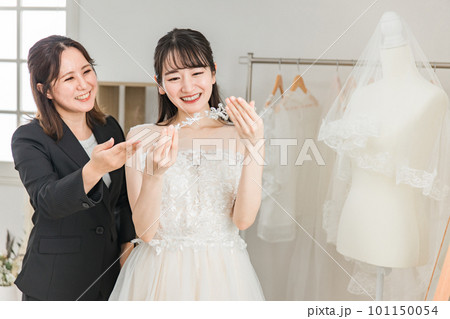 ヘッドドレス・髪飾りを選ぶウェディングドレスを着た花嫁とウェディングプランナーの女性 101150054