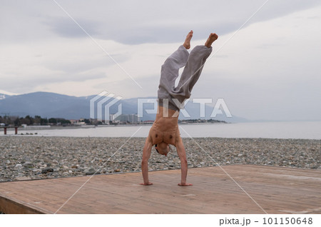 Shirtless caucasian man doing acrobatic wheel on the beach. Shirtless caucasian man doing acrobatic wheel on the beach. 101150648