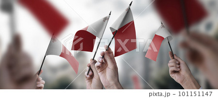 A group of people holding small flags of the Malta in their hands A group of people holding small flags of the Malta in their hands 101151147