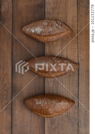 Freshly backed rye bread on wooden background. Three pieces of brown tommy on rustic background. Freshly backed rye bread on wooden background. Three pieces of brown tommy on rustic background. 101153779