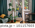 Smiling woman gardening on her balcony with cat 101157603