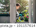 Smiling woman gardening on balcony on sunny day 101157614