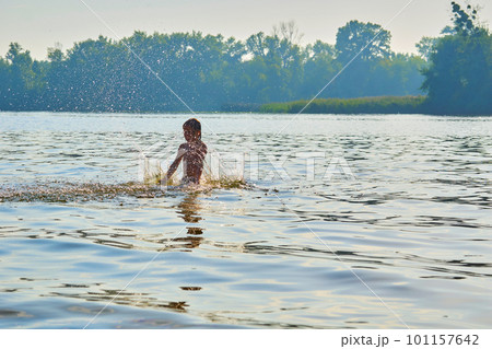 Pleased happy child bathes plays with splashes in a warm summer river, lake Pleased happy child bathes plays with splashes in a warm summer river, lake 101157642