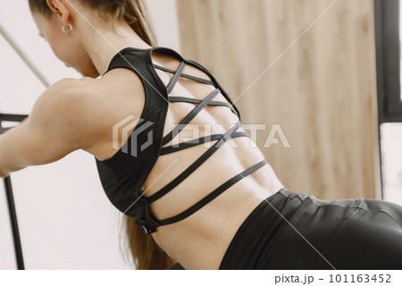 Close up photo of woman's back and her sportwear. Young fit woman training in gym. Woman wearing black sportwear. Close up photo of woman's back and her sportwear. Young fit woman training in gym. Woman wearing black sportwear. 101163452