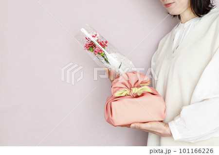 花束とプレゼントを持つ女性　ピンク背景　春のイメージ 101166226
