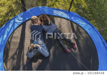 children look at the phone while lying on a trampoline children look at the phone while lying on a trampoline 101166438