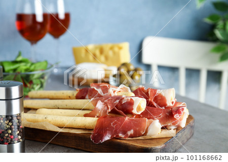 Tasty prosciutto with breadsticks on grey table 101168662